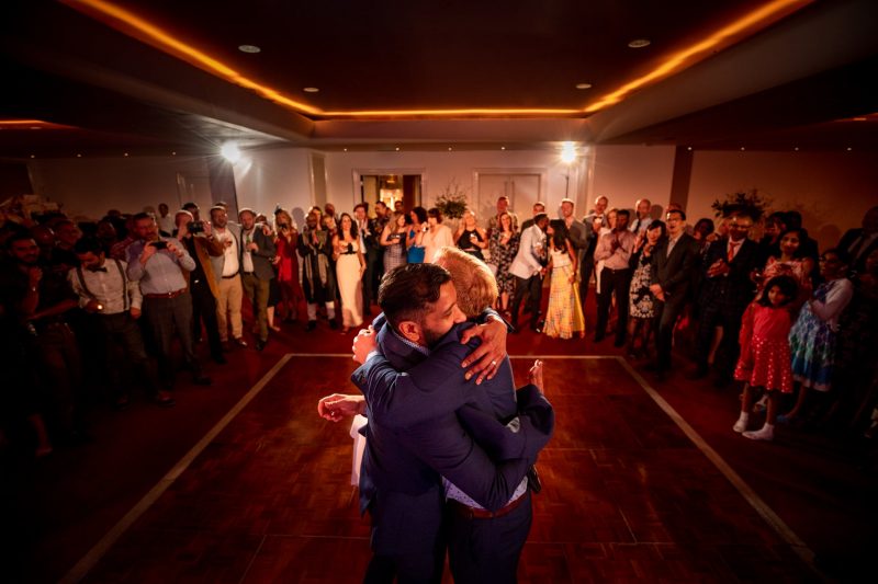 same-sex wedding hugging grooms